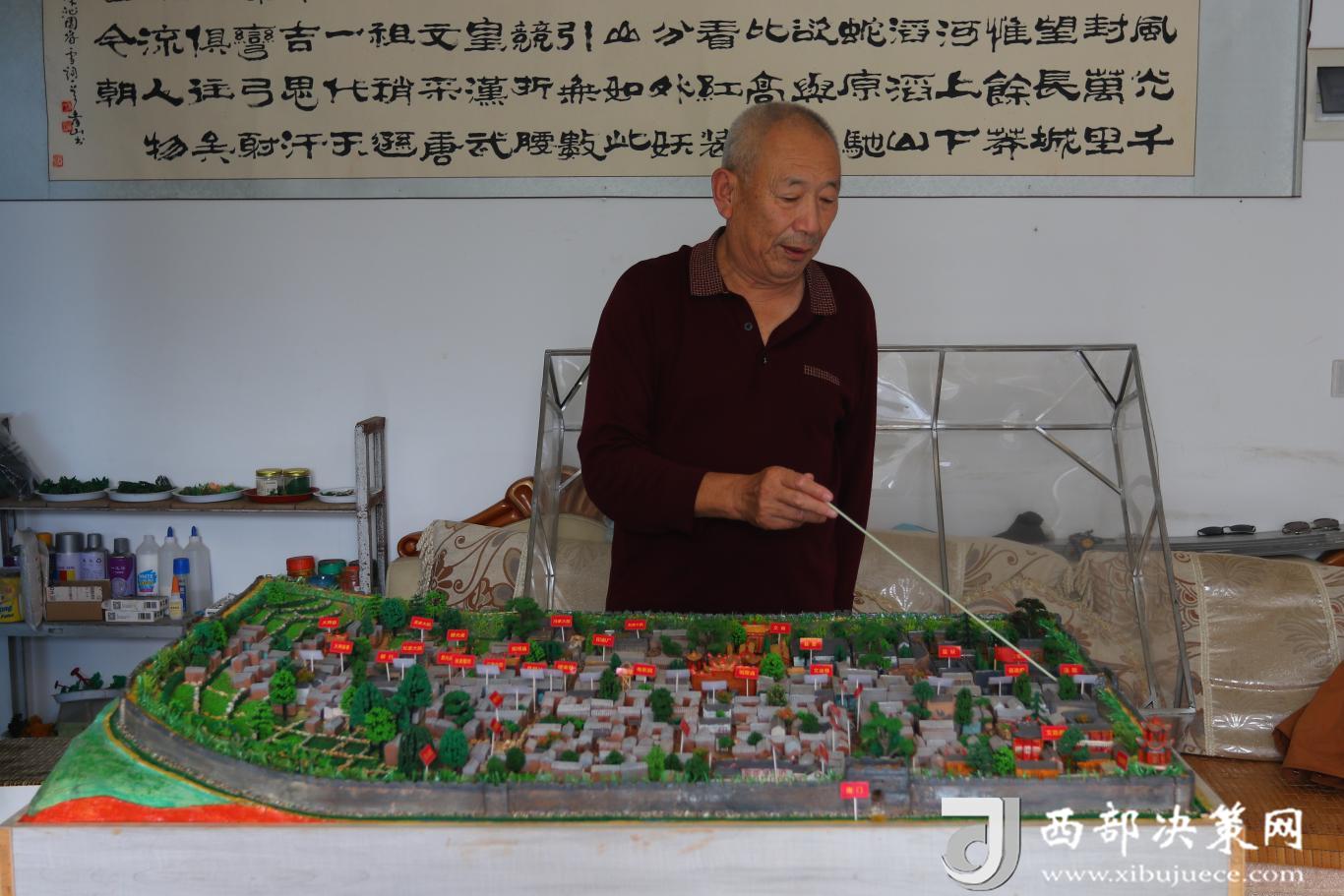 9月8日，庚春生向筆者介紹沙盤上的建筑